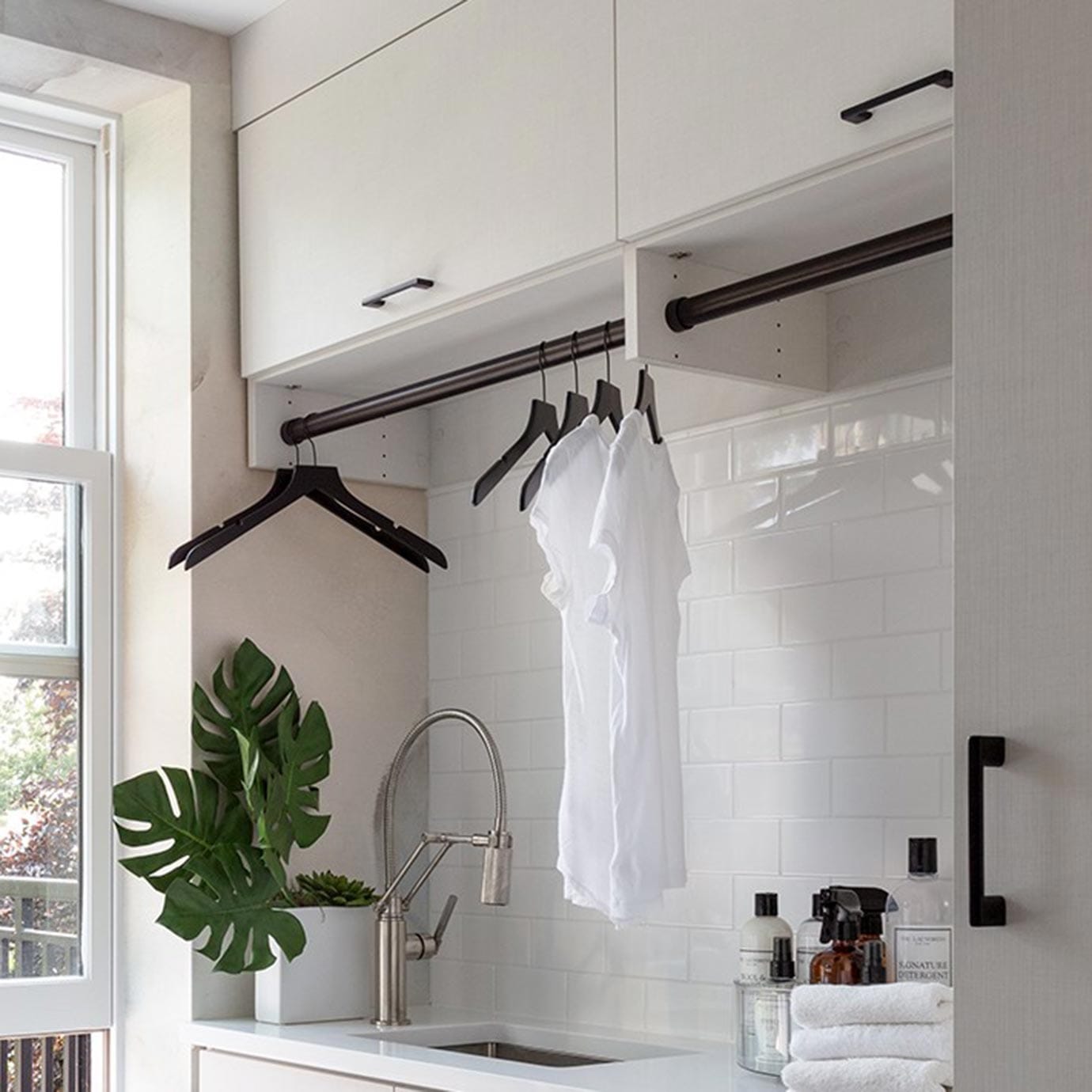 Custom laundry room with hanging poles for extra space in a white finish by California Closets