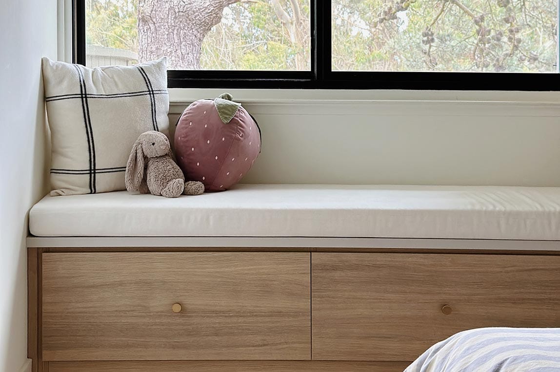 Custom built in bench storage next to window in a light wood finish California Closets