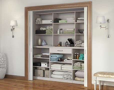 Hallway linens closet in reach in design with custom shelving and utility drawer by California Closets