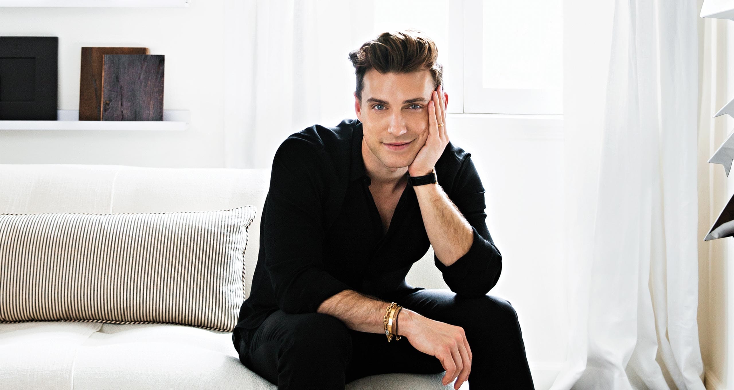 Jeremiah Brent in his Beverly Grove home with crisp white soafa, walls and striped pillow in Ideas of Order Magazine